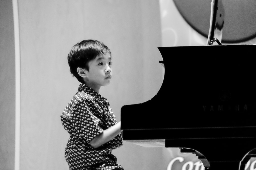 Young boy playing a piano.